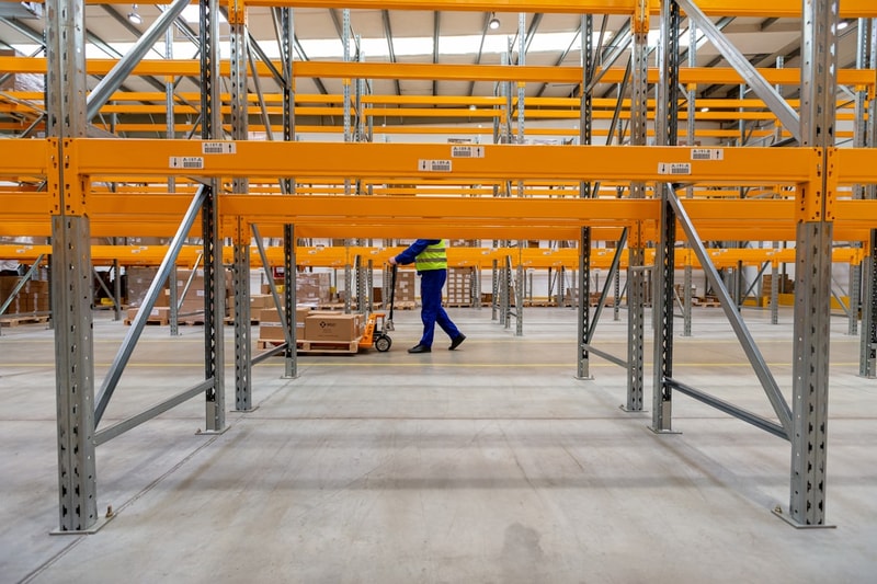 a man walking through a warehouse filled with lots of shelves